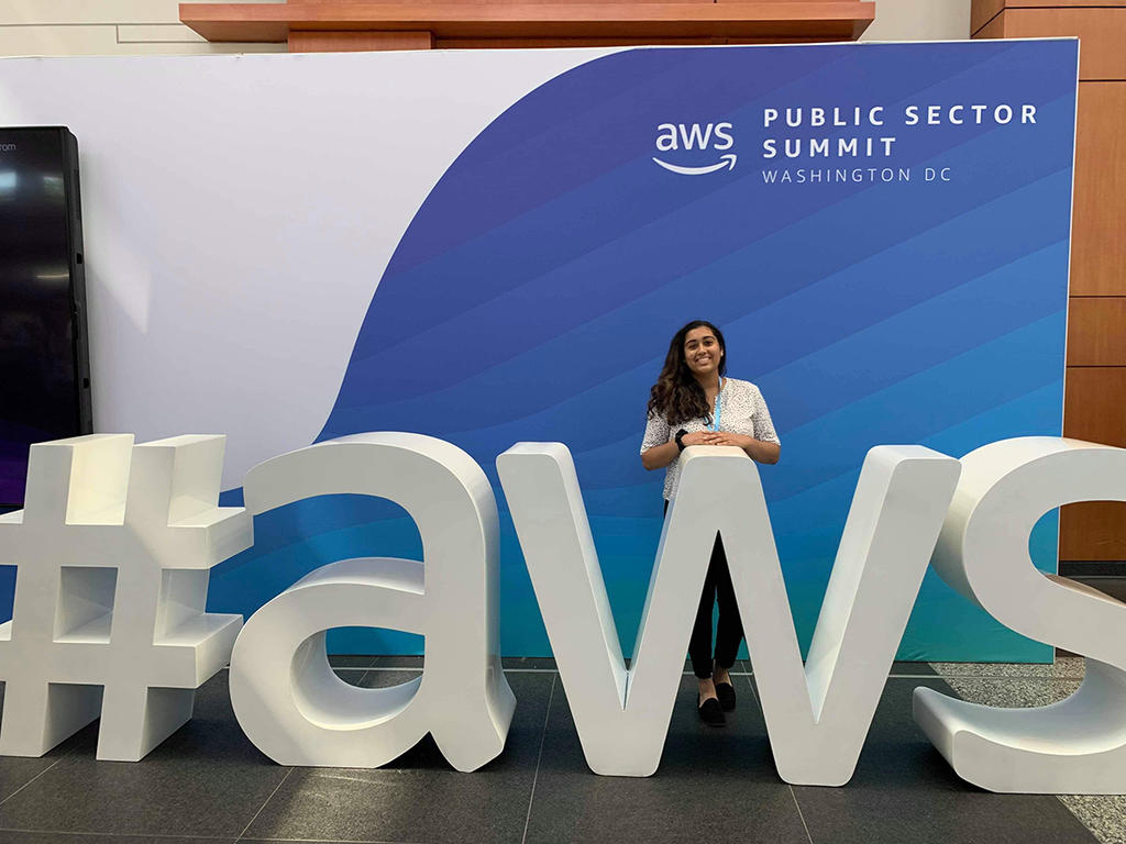 Maya Chatterjee standing behind big AWS letters, smiling at the camera